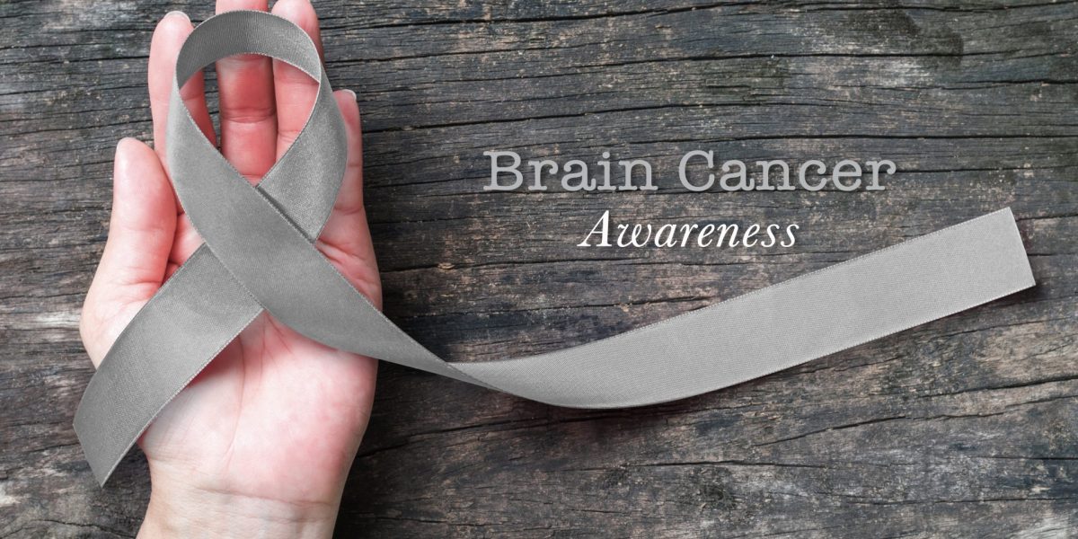 Brain cancer awareness, grey ribbon on helping hand